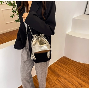 Détail du sac seau argenté avec bandoulière chaîne, glands et plis métallisés chic