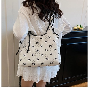 Detail of white canvas tote bag featuring black polka dots and small bow print patterns