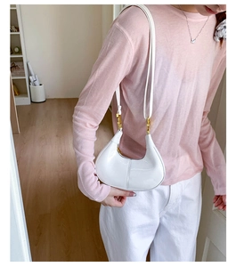 Detailed view of a white patent leather crescent shoulder bag with golden hardware