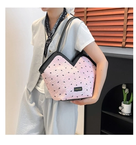 Detail of pink pleated bucket bag with bow prints and black V-shaped trim handle