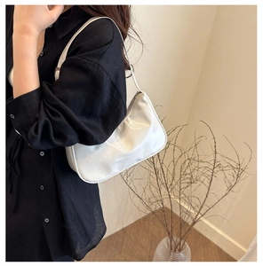 Close-up of minimalist white hobo bag with glossy finish and elegant pleated bottom detail