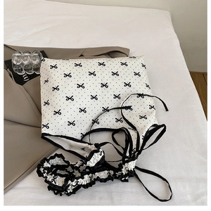 Detail of sweet white camisole with black polka dots, bow patterns, and ruffled trim edges