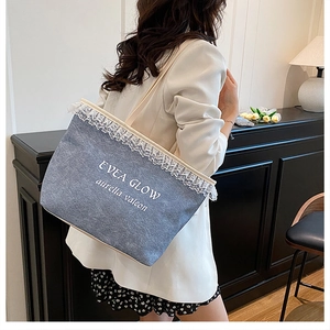 Blue denim tote bag with white lace trim and artistic lettering shown on shoulder