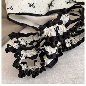 Detail of canvas bag with black polka dots, bow patterns and ruffled edge trim