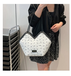 Close-up of white quilted tote bag with black bow embroidery and brand logo plate