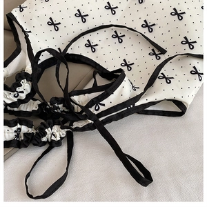 Detailed view of white polka dot canvas fabric with black bows and ruffled edges