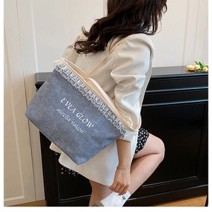 Detail of grey denim tote bag with white lace trim and Evea Glow artistic lettering print
