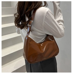 Detail of glossy brown wax leather crescent bag showing the polished texture and buckle