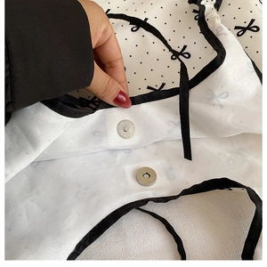 Detail of magnetic snap closure on white canvas bag with black bow polka dot pattern