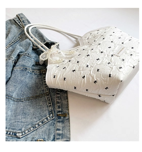 Détail du sac blanc avec motif K noir et poignée élégante ornée de perles blanches