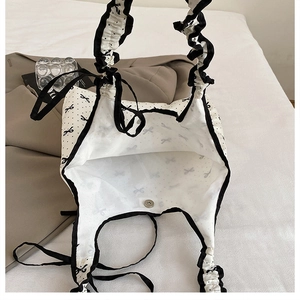 Close-up of bow print tote bag interior with magnetic closure and ruffle shoulder strap