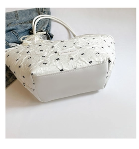 Détail du cabas matelassé blanc avec broderie nœud noir et breloque en perles chic