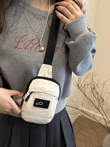 Minimalist beige nylon crossbody bag with black straps for casual daily outdoor use