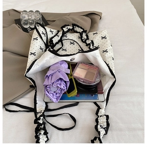 Spacious interior of white canvas tote bag with black bow patterns and ruffled edges