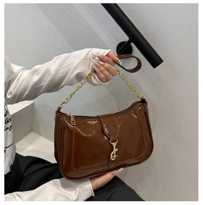 Détail du sac à bandoulière marron chocolat brillant avec chaîne dorée et boucle