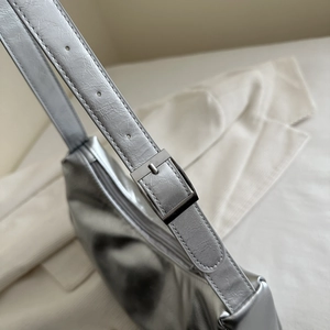 Detail of silver metallic crescent bag showing adjustable strap and buckle texture