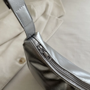 Detail of silver metallic crescent bag with wrinkled texture and smooth metal zipper