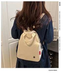 Close-up of beige canvas backpack featuring red Fashion label and adjustable shoulder straps