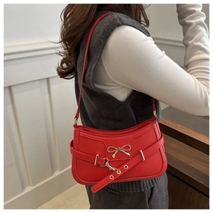 Detail of red shoulder bag with metal butterfly buckle and vintage strap design