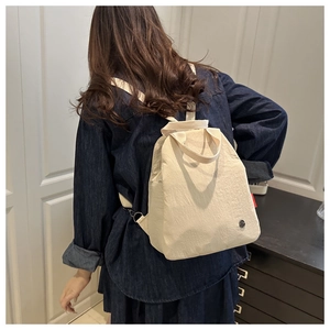 Detail of beige canvas backpack showing textile texture and red label on minimalist design