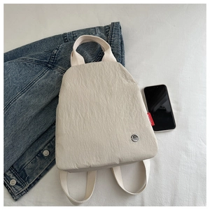 Detail of off-white wrinkled nylon backpack with M Fashion metal logo and red tag