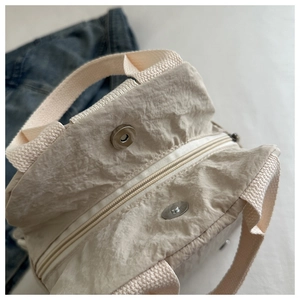 Detail view of beige pleated nylon crossbody bag with zipper and magnetic closure