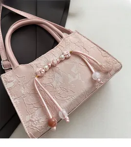 Detailed close-up of pink lace handbag featuring pearl beads and delicate floral textures