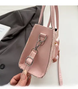 Macro detail of a light pink handbag showing silver D-ring hardware and lace texture