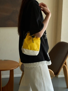 Bolso saco minimalista amarillo y beige con cordón y correa de hombro negra ajustable