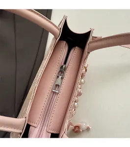 Top view detail of pink crossbody bag showing smooth zipper closure and floral pearl decor