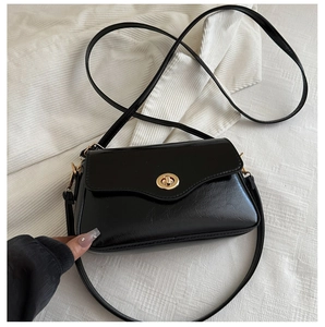 Close-up of shiny patent leather crossbody bag with elegant gold oval twist lock closure
