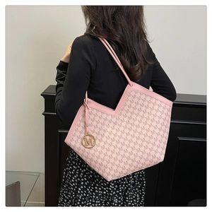 Detailed view of pink tote bag featuring all-over M pattern and gold metallic M pendant