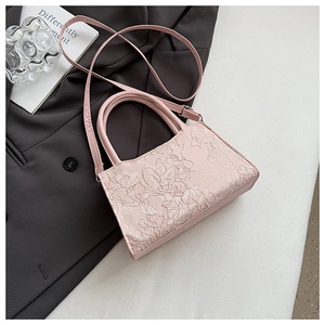 Detail of light pink lace embroidery with 3D floral textures on the crossbody bag