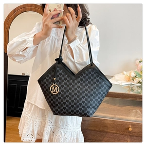 Sac cabas noir à monogramme avec anses en cuir porté par un mannequin en robe de dentelle