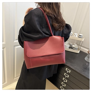 Detail view of burgundy tote bag with long handles and matte leather finish on a shoulder