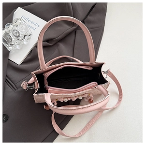 Detailed interior view of pink handbag with multiple compartments and pearl charm