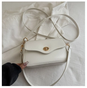 Detail of white faux leather crossbody bag with golden round metal twist lock