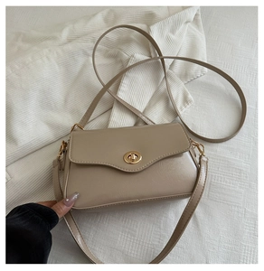 Detail of beige faux leather crossbody bag showing a golden circular twist lock closure