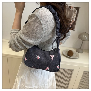 Detail of denim shoulder bag with pink rose embroidery and ruffled drawstring strap