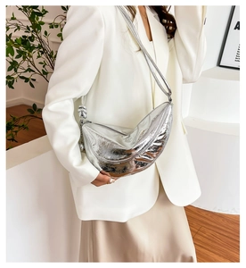 Detail der silbernen halbmondförmigen Tasche mit Metallic-Struktur und verstellbarem Riemen