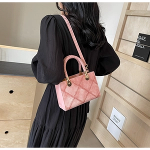 Pink quilted crossbody bag with braided handle and gold hardware on model back view
