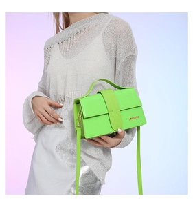 Detail of neon green textured handbag with gold logo and elegant metallic handle