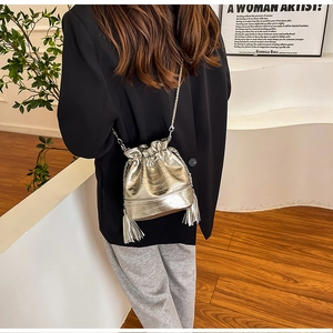 Dettaglio della borsa a secchiello plissettata argento con catena e frange su modella