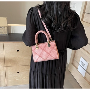 Close-up of pink quilted crossbody bag featuring woven handles and gold metal hardware