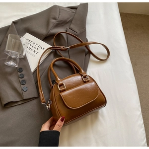Detail of caramel pleated Boston bag on grey suit with silver hardware and front pocket
