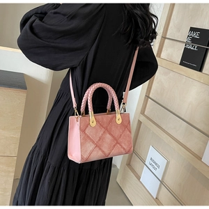Detail of pink quilted crossbody bag with woven handle and gold hardware on black dress