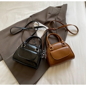 Detailed view of mini shell bowling bags in black and brown textured faux leather