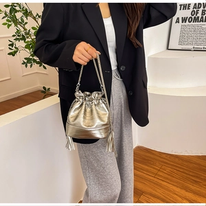 Dettaglio borsa a secchiello argento con chiusura a coulisse plissettata e frange
