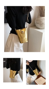 Détail du sac seau doré avec texture métallique, bandoulière chaîne et fermoir en cuir