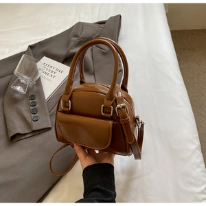 Detail view of brown vintage PU leather shell bag with silver buckle and small front pocket
